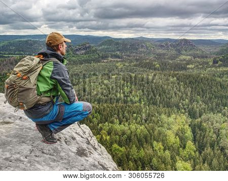 Man Tourist In Nature. Spring Free Day In Rocky Mountains. Hiker With Sporty Backpack Stand On Rocky