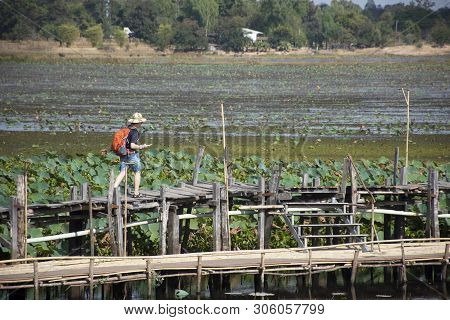 Thai People And Foreigner Travelers Travel And Walking Visit On Kae Dam Long Wood Bridge At Mahasara