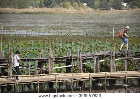 Thai People And Foreigner Travelers Travel And Walking Visit On Kae Dam Long Wood Bridge At Mahasara