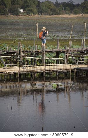 Thai People And Foreigner Travelers Travel And Walking Visit On Kae Dam Long Wood Bridge At Mahasara