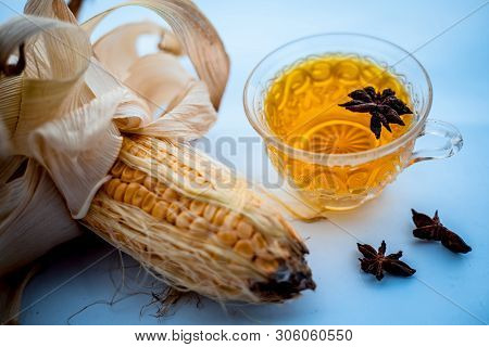Beneficial Detoxifying Corn Tea In A Glass Cup Isolated On White Along With Some Star Anise Spice.ra