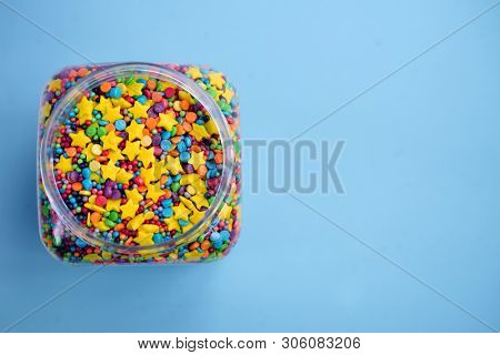 Colorful sugar sprinkles on a blue background. Big can