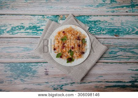 Salad Of Fermented Cabbage And Cranberries With Herbs Stands On A Wooden Blue Table On A Linen Napki