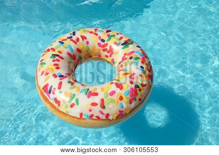 Bright Inflatable Doughnut Ring Floating In Swimming Pool On Sunny Day