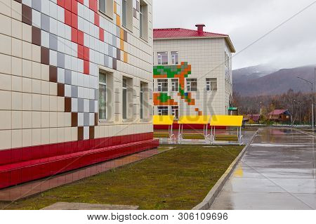 Esso, Kamchatka Peninsula, Russia- 02 October 2014: School Building Exterior With Playground On A We