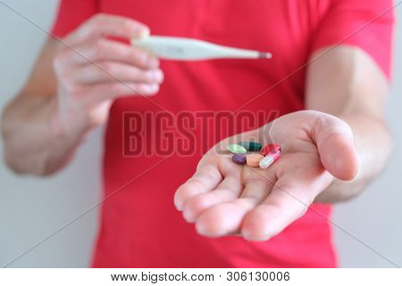 A Man With A Thermometer In His Hand. Elevated Body Temperature. Cold And Flu Pills. Prevention And 