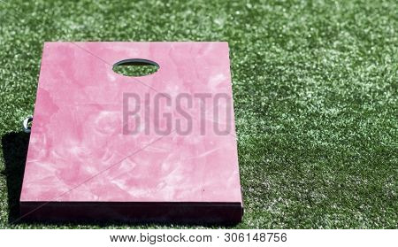 A Wooden Corn Hole Game Is Made Out Of Plywood, Painted Red Aith A Medal Handle On The Side To Carry