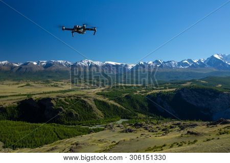 ALTAI MOUNTAINS / RUSSIA - AUGUST 08, 2018: Drone DJI Mavic Pro hovers in the air with the snow capped mountains of the Northern Chuysky Range on the background