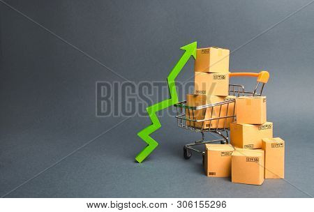 Shopping Cart With Cardboard Boxes And A Green Up Arrow. Increase The Pace Of Sales And Production O