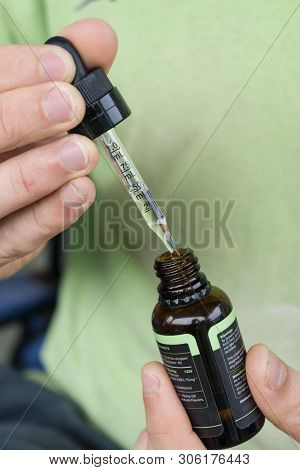 Measuring The Correct Amount Of Cbd Oil From A Brown Tincture Bottle.