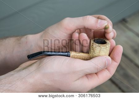 Caucasian Male Packing A Corn Cobb Pipe With Marijuana.