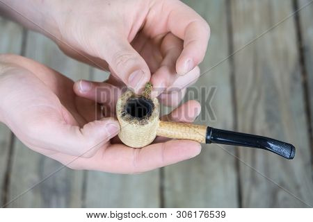 Caucasian Male Packing A Corn Cobb Pipe With Marijuana.