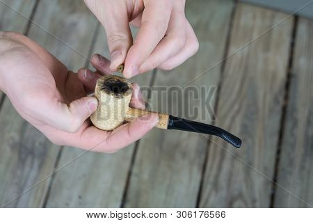 Caucasian Male Packing A Corn Cobb Pipe With Marijuana.