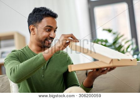 food delivery, consumption and people concept - excited indian man looking inside of takeaway pizza box at home