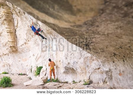 Athletic Man Climbs A Hard Overhanging Route 8c-9a Category With Rope. Sport Climbing, Lead. Side Vi