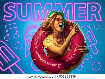 Female Model In Trendy Neon Light On Blue Background. Modern Design. Beautiful Young Woman Posing In