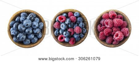 Ripe Raspberries And Blueberries On A Wooden Bowl. Raspberries And Blueberries Isolated On White Bac
