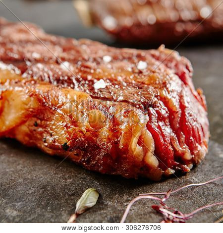 Hot Grilled Whole Tri-tip Steak on Black Stone Background. Fresh Juicy Medium Rare Beef Grillsteak. Barbecue Meat Close Up