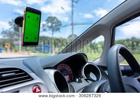 Young Asian Man Driver A Car In Town And Smartphone With Green Blank Screen Attached To The Windshie