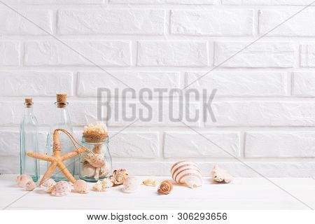 Sea Or Ocean Decorations Near By White Brick Wall. Blue Bottles With Shells, Starfish. Selective Foc