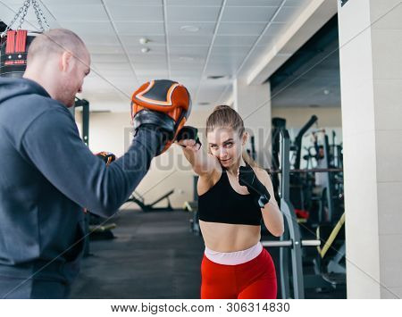 Fit Blonde Woman Training  Punch With Man Trainer.  At The Gym. Couple Exercising Punching