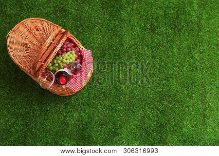 Picnic Basket With Wine And Grapes On Grass, Top View. Space For Text