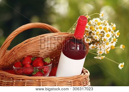 Picnic Basket With Wine, Strawberries And Flowers On Blurred Background, Closeup