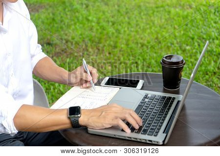 Young Buseness Man Work On The Table With His Laptop And Coffee In Garden Outdoor Loaction