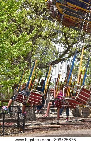 A Chair Swing Full Of Young Children Provide Entertainment At An Amusement Park.