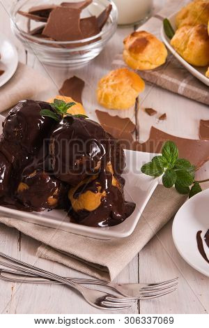 Chocolate Profiteroles With Whipped Cream On White Dish.