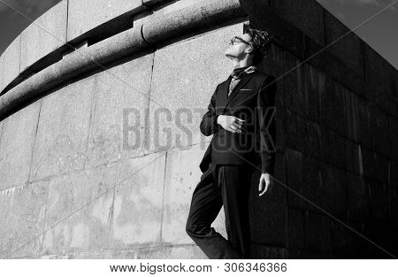 handsome fashion male model dressed in elegant suit posing outdooe. Long haired Metrosexual. Black and white picture.