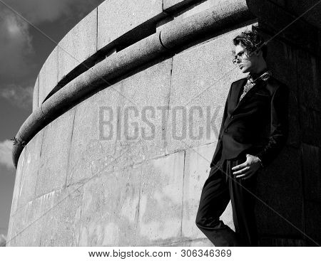 handsome fashion male model dressed in elegant suit posing outdooe. Long haired Metrosexual. Black and white picture.