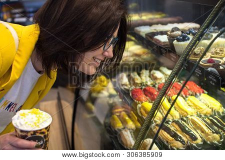 The Concept Of Diet And Sweet. Sweet Tooth Girl In A Candy Store Looking At A Glass Window With Colo