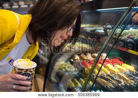 The Concept Of Diet And Sweet. Sweet Tooth Girl In A Candy Store Looking At A Glass Window With Colo