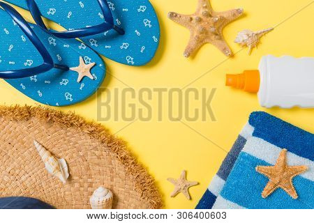 Flip Flops, Straw Hat, Starfish, Sunscreen Bottle, Body Lotion Spray On Yellow Background Top View .