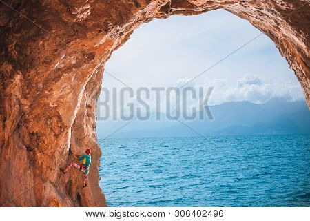 Strong Girl Climbs A Climbing Route. A Woman Goes In For Sports In Nature. The Athlete Climbs A Rock