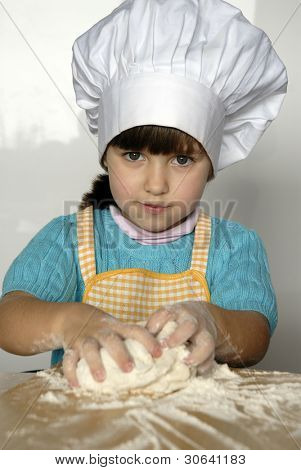 Bambina cucinare una pizza in una cucina.Ragazzino in una cucina.