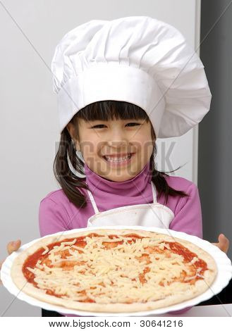 Piccola ragazza in possesso di una pizza.Bambina con un tappo di chef tenendo una pizza.