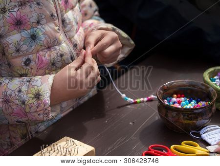 Girl Making Necklace From Beads
