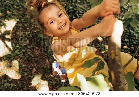Outdoors Image Of Adorable Cute Blond Little Girl Playing And Smiling Broadly At Nature Background. 