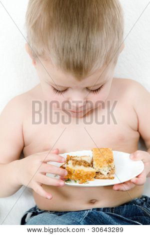 O menino de idade escolar com um bolo nas mãos