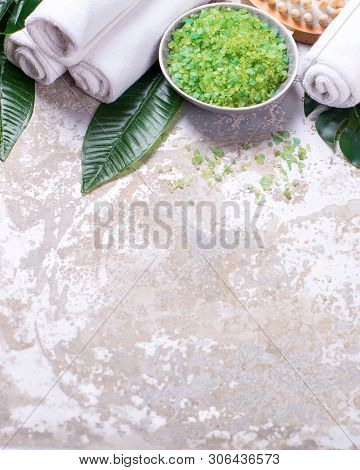 Wellnes Spa  Border. Bowl With Green  Sea Salt, Towels, Massage Tool, Tropical Leaves  On Grey Textu