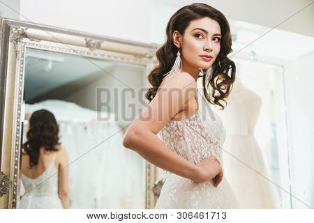 Beautifu bride choosing wedding dress in a wedding salon