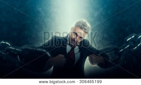 Confident and angry business man breaking chain. Business concept of liberation from credit slavery