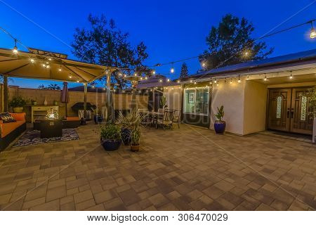 Patio Of Home With Seating Area Under A Gazebo And Dining Area Under An Umbrella
