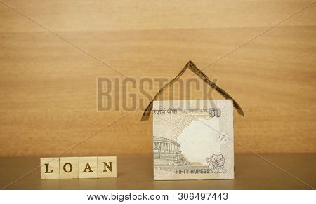 House Made From The Indian Currency Notes And Home Loan In Wooden Block Letters On Wooden Background