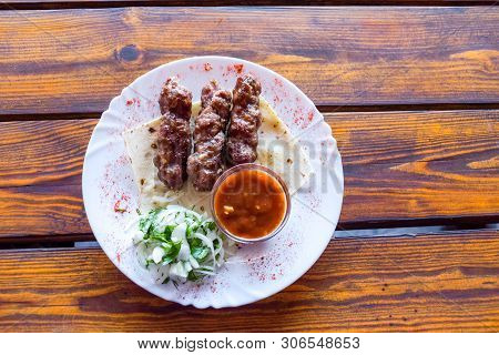 Portion Luleh Kebab On A Plate. Appetizing Dish On The Wooden Brown Table.