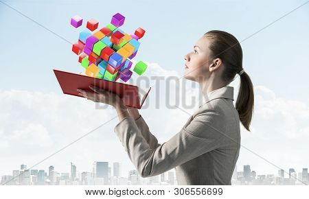 Woman Looks At Flying Colorful 3d Cubes Above Open Book. Hi-tech Concept With Virtual Reality Abstra