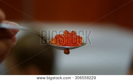 Appetesing Red Salted Caviar In Spoon Isolated In Hand