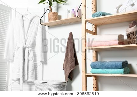 Clean Towels And Robe Near White Wall In Modern Bathroom Interior